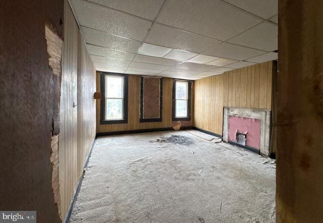 324 Fulton Ave, Baltimore, MD 21223 - carpeted empty room featuring a drop ceiling, wooden walls, and a fireplace