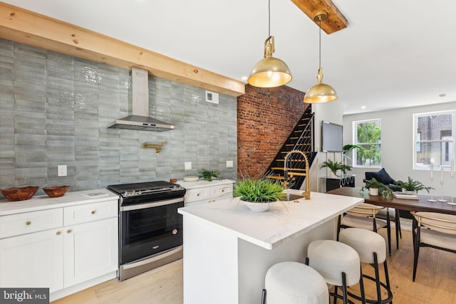 2165 E Gordon St, Philadelphia, PA 19125 - kitchen featuring stainless steel gas stove, wall chimney exhaust hood, light wood-type flooring, and white cabinets