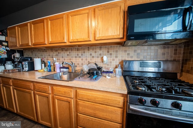 5563 Cedonia Ave, Baltimore, MD 21206 - kitchen with stainless steel gas stove, black microwave, light countertops, backsplash, and brown cabinetry
