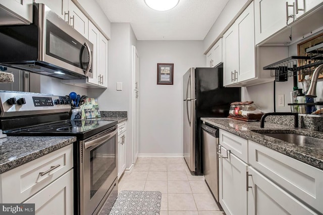 1515 Lincoln Way Unit 304B, Mclean, VA 22102 - kitchen featuring stainless steel appliances, white cabinetry, light tile patterned floors, dark stone countertops, and a textured ceiling