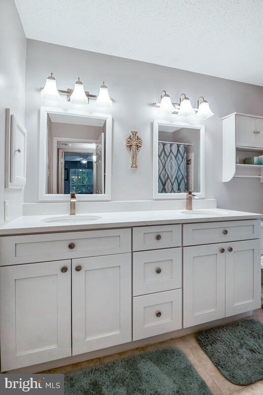 1515 Lincoln Way Unit 304B, Mclean, VA 22102 - bathroom with double vanity, a textured ceiling, tile patterned floors, and a shower with curtain