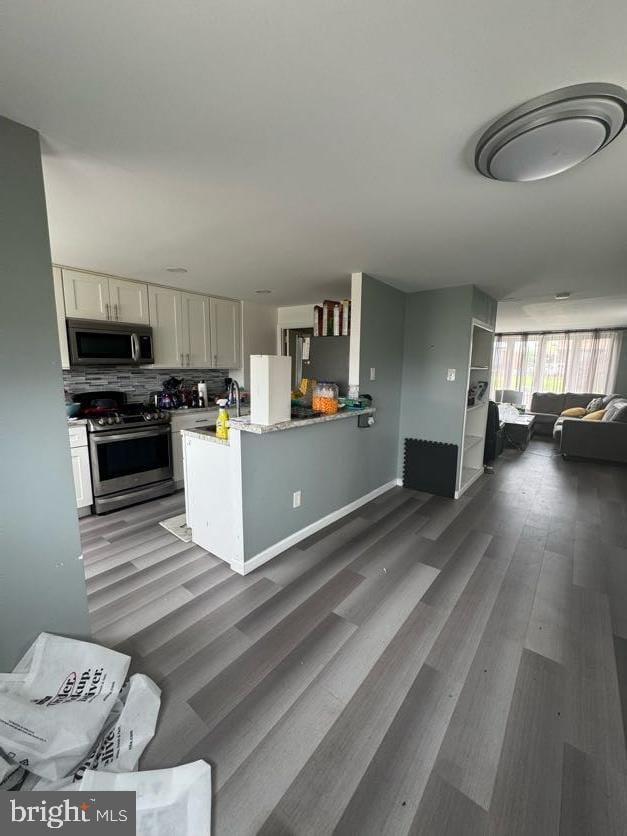 3430 Eden St, Philadelphia, PA 19114 - kitchen featuring appliances with stainless steel finishes, open floor plan, wood finished floors, decorative backsplash, and white cabinetry