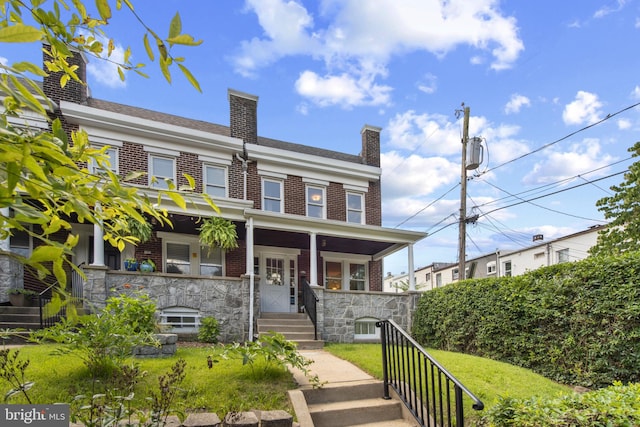 1125 Woodheights Ave, Baltimore, MD 21211 - view of front of house featuring brick siding, a porch, a chimney, and stone siding