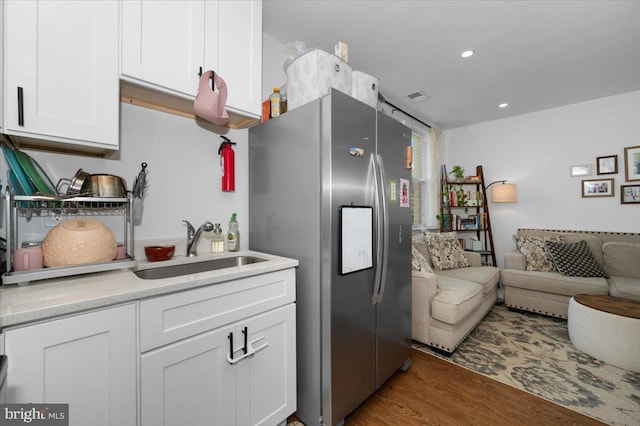 211 Webster St NE, Washington, DC 20011 - kitchen featuring stainless steel refrigerator with ice dispenser, white cabinets, wood finished floors, light countertops, and open floor plan