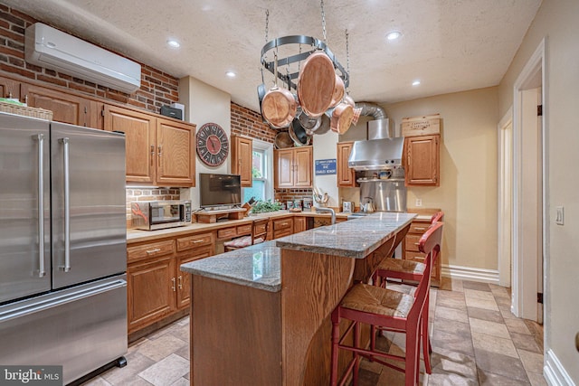 407 N 8th St, Allentown, PA 18102 - kitchen with stainless steel appliances, a wall mounted AC, wall chimney range hood, stone tile floors, and a textured ceiling