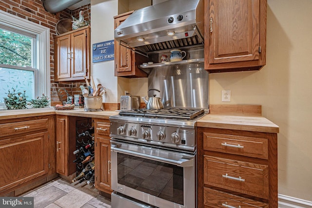 407 N 8th St, Allentown, PA 18102 - kitchen with stainless steel range, wall chimney exhaust hood, butcher block countertops, brown cabinets, and light stone finish floors
