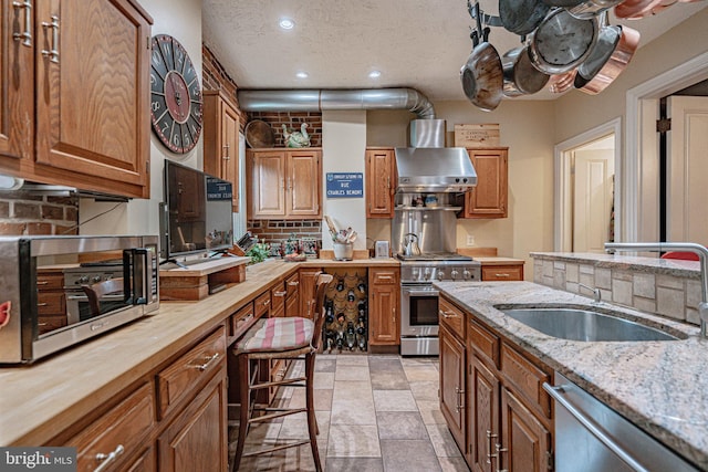 407 N 8th St, Allentown, PA 18102 - kitchen with appliances with stainless steel finishes, wall chimney range hood, wooden counters, recessed lighting, and brown cabinetry