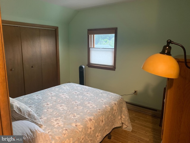 21055 Bayside Ave, Rock Hall, MD 21661 - bedroom with wood finished floors, lofted ceiling, a baseboard heating unit, and a closet