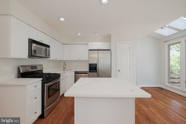 6110 Joust Ln, Alexandria, VA 22315 - kitchen with stainless steel appliances, a skylight, a center island, light wood-type flooring, and recessed lighting