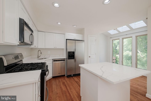 6110 Joust Ln, Alexandria, VA 22315 - kitchen featuring stainless steel appliances, a skylight, white cabinetry, light wood-style flooring, and recessed lighting