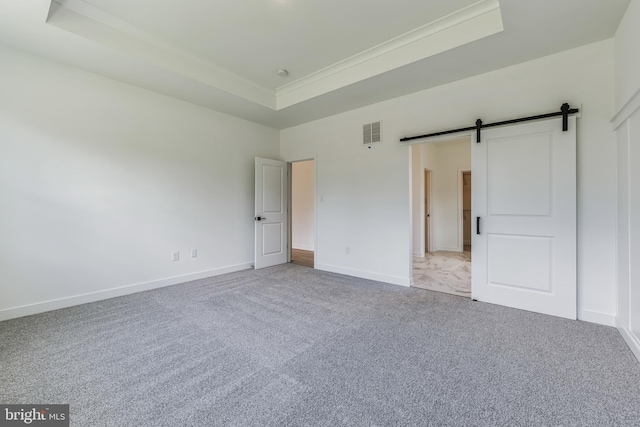 168 Tall Oak Dr, Felton, DE 19943 - unfurnished bedroom featuring a raised ceiling, carpet flooring, and a barn door