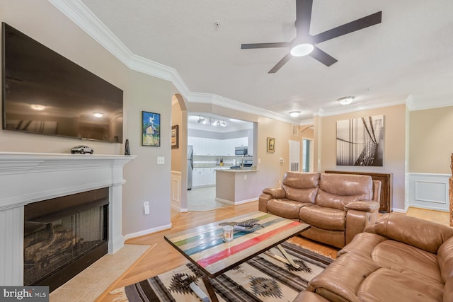 7 Booth St Unit 202, Gaithersburg, MD 20878 - living room featuring crown molding, ceiling fan, a fireplace with flush hearth, light wood-type flooring, and arched walkways