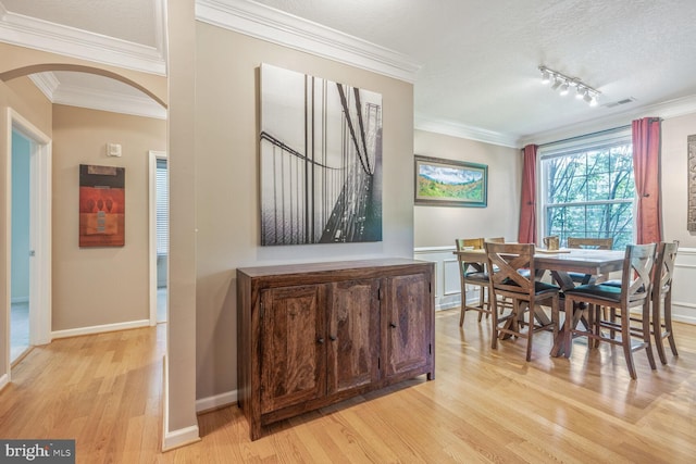 7 Booth St Unit 202, Gaithersburg, MD 20878 - dining space featuring arched walkways, light wood-style floors, ornamental molding, track lighting, and a textured ceiling
