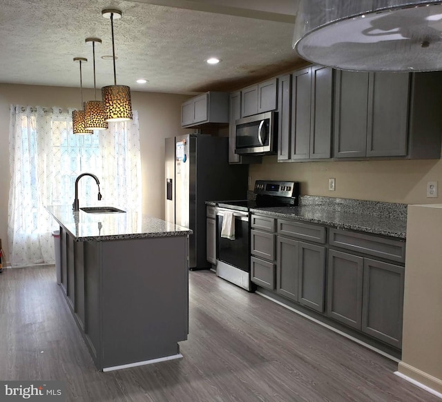 15021 Mcknew Rd, Burtonsville, MD 20866 - kitchen featuring appliances with stainless steel finishes, gray cabinets, dark wood-type flooring, a textured ceiling, and a center island with sink