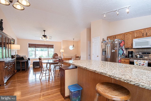 75 Westminster Dr, Front Royal, VA 22630 - kitchen with stainless steel appliances, a ceiling fan, rail lighting, light wood-style flooring, and a kitchen bar