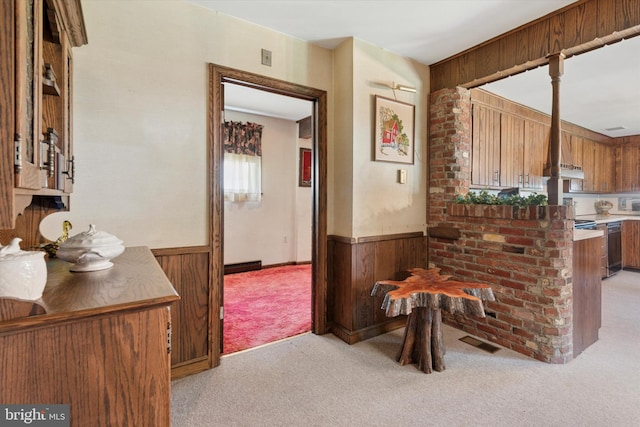 301 W Marshall St, West Chester, PA 19380 - kitchen with light colored carpet, wooden walls, wainscoting, brown cabinetry, and under cabinet range hood