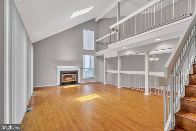 22 Witch Hazel Ct, Monmouth Junction, NJ 08852 - unfurnished living room with high vaulted ceiling, a skylight, a fireplace with flush hearth, stairway, and wood finished floors