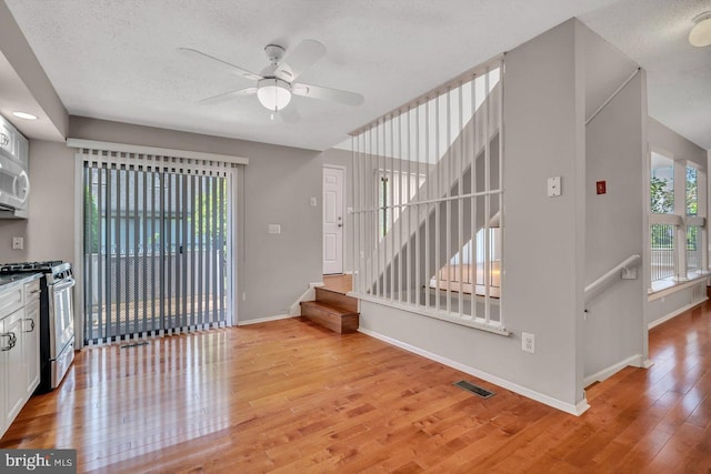 22 Witch Hazel Ct, Monmouth Junction, NJ 08852 - kitchen with stainless steel gas stove, light wood-type flooring, ceiling fan, a textured ceiling, and white cabinets