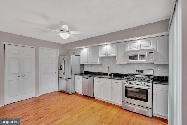 22 Witch Hazel Ct, Monmouth Junction, NJ 08852 - kitchen with appliances with stainless steel finishes, dark countertops, decorative backsplash, ceiling fan, and light wood finished floors