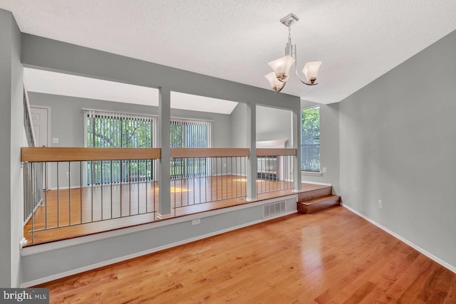 22 Witch Hazel Ct, Monmouth Junction, NJ 08852 - empty room featuring wood finished floors, a textured ceiling, and a chandelier