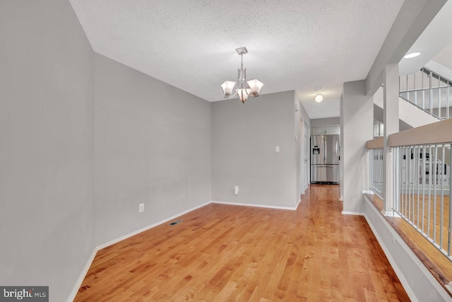22 Witch Hazel Ct, Monmouth Junction, NJ 08852 - unfurnished room with a chandelier, light wood-style floors, and a textured ceiling