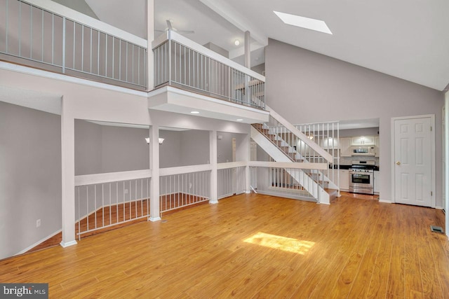 22 Witch Hazel Ct, Monmouth Junction, NJ 08852 - unfurnished living room with stairway, high vaulted ceiling, a skylight, and light wood-type flooring