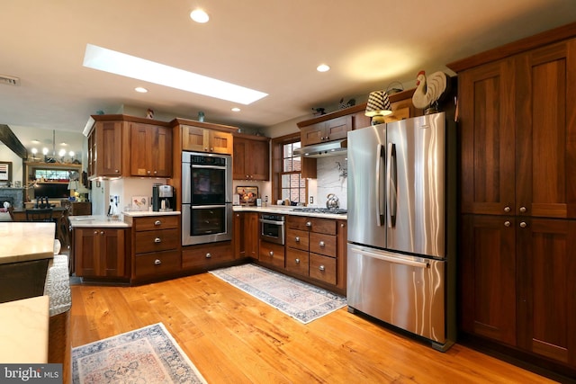320 Hartswick Ave, State College, PA 16803 - kitchen with appliances with stainless steel finishes, light countertops, under cabinet range hood, light wood-style floors, and a skylight