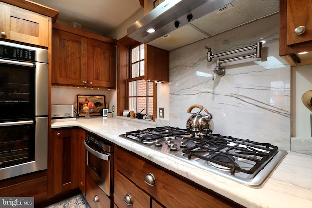 320 Hartswick Ave, State College, PA 16803 - kitchen featuring appliances with stainless steel finishes, ventilation hood, light stone counters, and brown cabinets