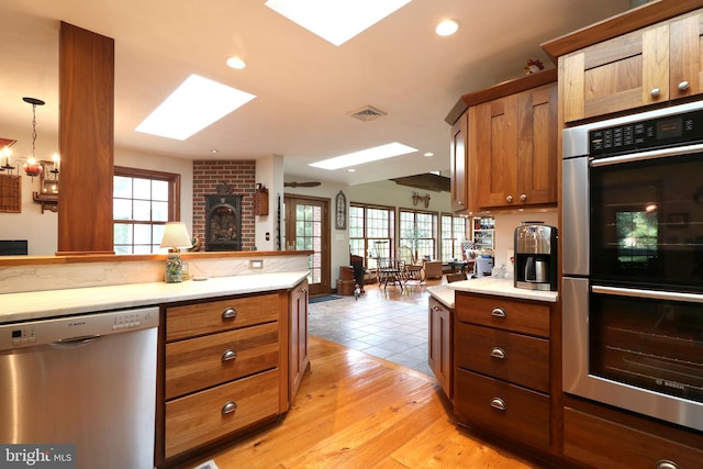 320 Hartswick Ave, State College, PA 16803 - kitchen featuring stainless steel appliances, a skylight, brown cabinetry, light countertops, and plenty of natural light