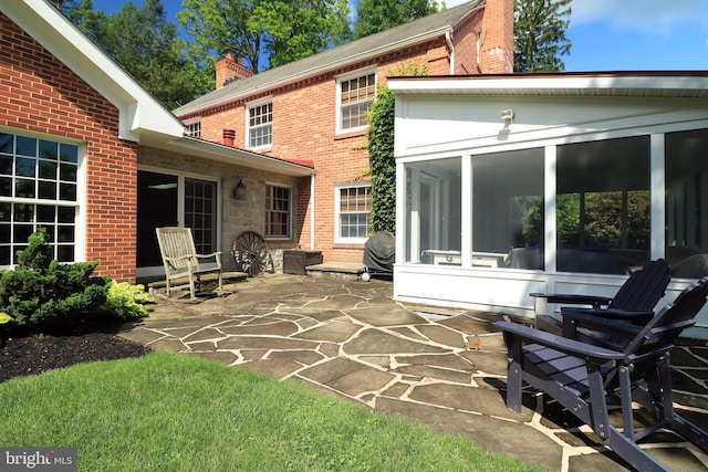 320 Hartswick Ave, State College, PA 16803 - rear view of property featuring a sunroom, a chimney, brick siding, and a patio area