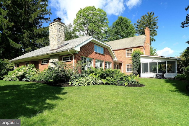 320 Hartswick Ave, State College, PA 16803 - back of house featuring a chimney, a lawn, brick siding, and a sunroom