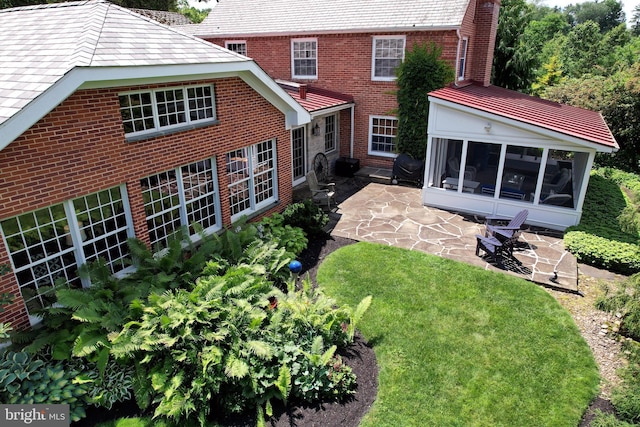 320 Hartswick Ave, State College, PA 16803 - rear view of property featuring a patio, a sunroom, brick siding, a yard, and a high end roof