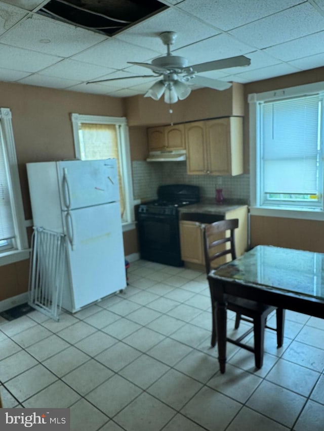 221 Buchanan Ave, Hamilton, NJ 08610 - kitchen with black range with gas stovetop, under cabinet range hood, freestanding refrigerator, a drop ceiling, and healthy amount of natural light