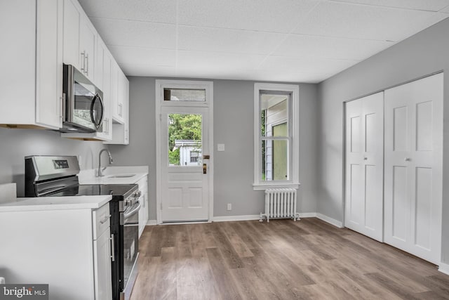345-347 W Penn St, Carlisle, PA 17013 - kitchen featuring appliances with stainless steel finishes, radiator, wood finished floors, white cabinets, and a drop ceiling