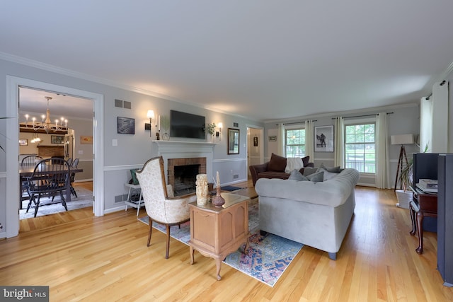 1228 Hunsicker Rd, Lancaster, PA 17601 - living room with crown molding, a brick fireplace, light wood finished floors, and a chandelier