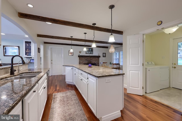 1228 Hunsicker Rd, Lancaster, PA 17601 - kitchen with washer and dryer, dark wood-style floors, a brick fireplace, white cabinets, and beamed ceiling