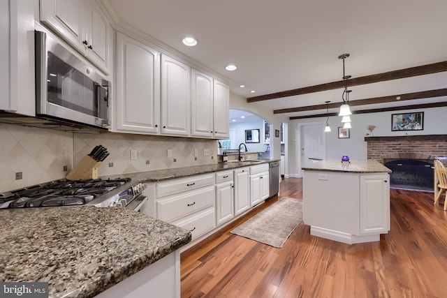 1228 Hunsicker Rd, Lancaster, PA 17601 - kitchen with stainless steel appliances, a fireplace, arched walkways, wood finished floors, and white cabinetry