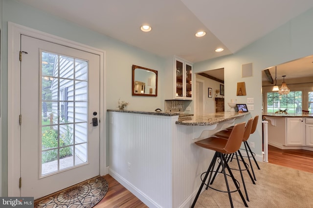 1228 Hunsicker Rd, Lancaster, PA 17601 - kitchen featuring light wood-style floors, recessed lighting, white cabinets, a breakfast bar, and glass insert cabinets
