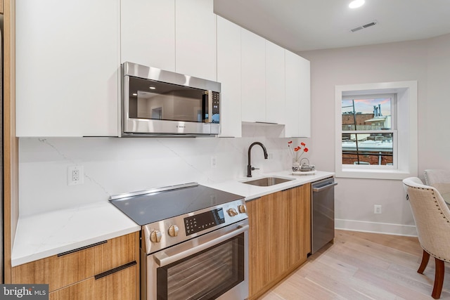 1724 Connecticut Ave NW Unit 2, Washington, DC 20009 - kitchen with appliances with stainless steel finishes, light wood-style flooring, tasteful backsplash, modern cabinets, and white cabinetry