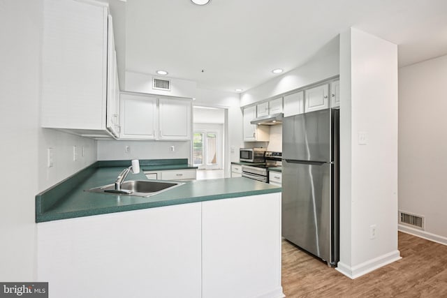450 Hartford Sq Unit 7, West Chester, PA 19380 - kitchen with stainless steel appliances, under cabinet range hood, a peninsula, light wood-style floors, and dark countertops