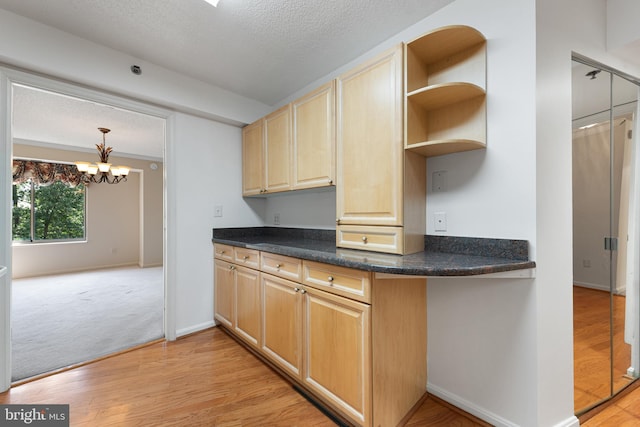 19385 Cypress Ridge Ter Unit 503, Leesburg, VA 20176 - kitchen with light brown cabinetry, light wood finished floors, dark countertops, a textured ceiling, and a chandelier