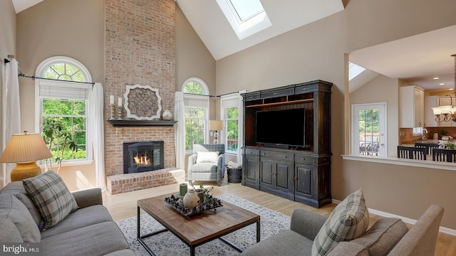 24 Montfort Dr, Belle Mead, NJ 08502 - living area with high vaulted ceiling, light wood-style floors, a skylight, a brick fireplace, and a chandelier
