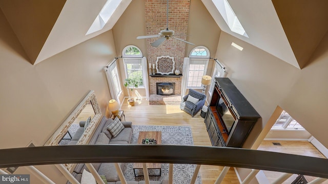 24 Montfort Dr, Belle Mead, NJ 08502 - living area with a skylight, high vaulted ceiling, wood finished floors, healthy amount of natural light, and a brick fireplace