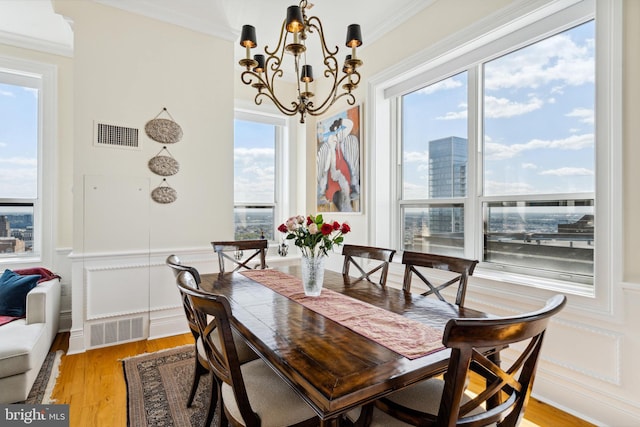 1425 Locust St Unit 33A, Philadelphia, PA 19102 - dining area with a chandelier, a decorative wall, a wainscoted wall, light wood finished floors, and crown molding