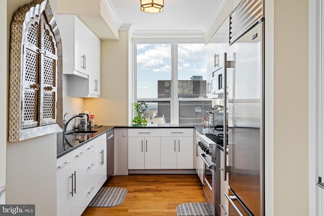 1425 Locust St Unit 33A, Philadelphia, PA 19102 - kitchen with high end appliances, crown molding, light wood-style floors, white cabinets, and floor to ceiling windows