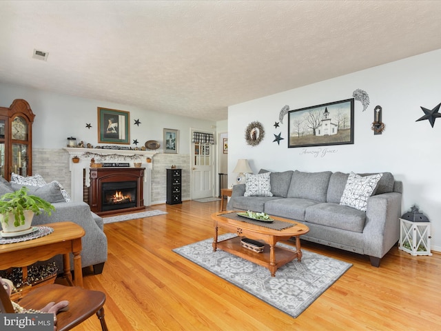117 Amherst Ct, Stephens City, VA 22655 - living room with light wood-style floors, a warm lit fireplace, and a textured ceiling