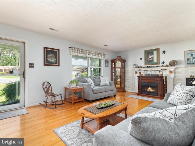117 Amherst Ct, Stephens City, VA 22655 - living room featuring healthy amount of natural light, a textured ceiling, a warm lit fireplace, and wood finished floors