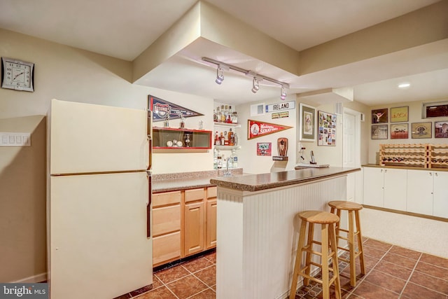 20304 Watkins Meadow Dr, Germantown, MD 20876 - kitchen featuring freestanding refrigerator, dark tile patterned floors, track lighting, and a breakfast bar area