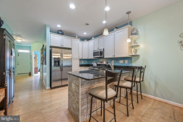 147 Candor Ln, Dover, DE 19901 - kitchen featuring appliances with stainless steel finishes, a peninsula, light wood-style flooring, dark stone countertops, and a breakfast bar