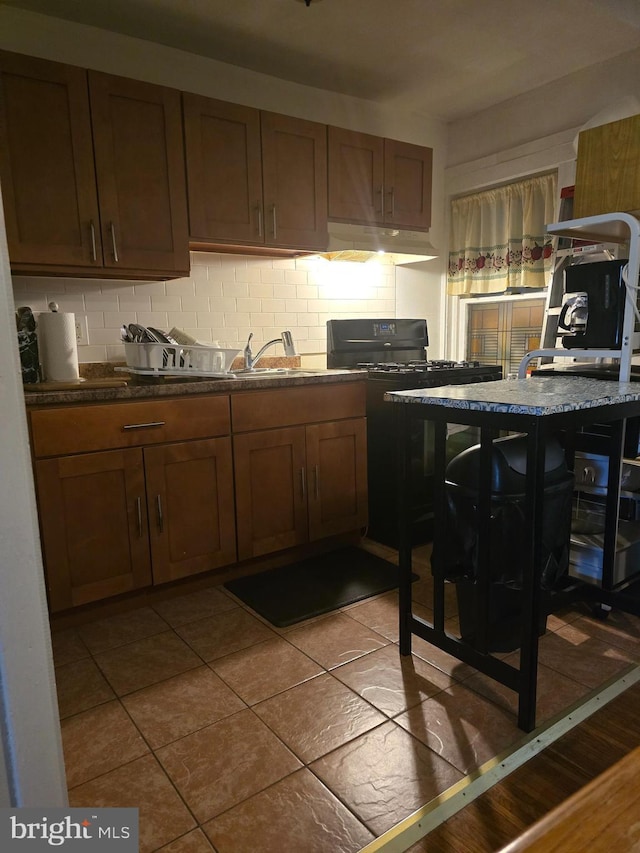 306 E Queen Ln, Philadelphia, PA 19144 - kitchen featuring under cabinet range hood, decorative backsplash, gas stove, and dark countertops